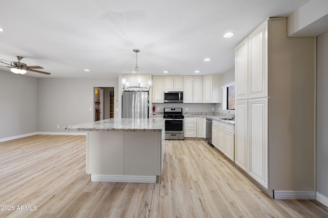 kitchen with recessed lighting, a center island, appliances with stainless steel finishes, light wood-type flooring, and light stone countertops