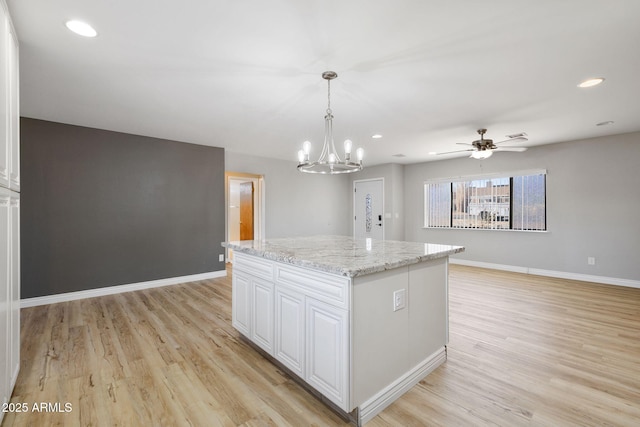 kitchen with a center island, white cabinets, light wood-style flooring, and baseboards