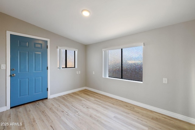 interior space with light wood-type flooring, lofted ceiling, and baseboards