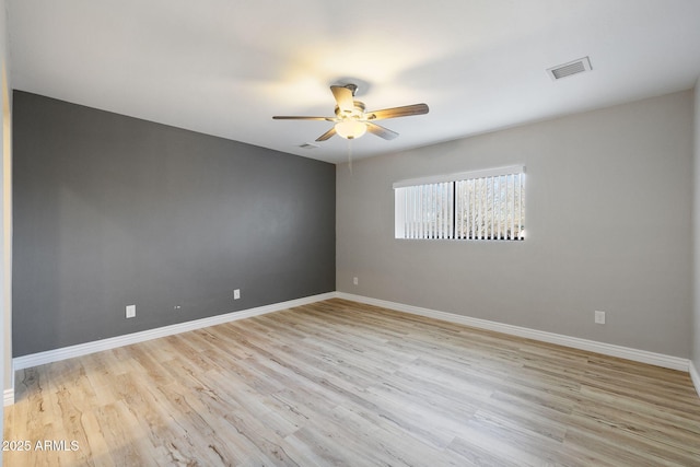 spare room with light wood finished floors, baseboards, and visible vents