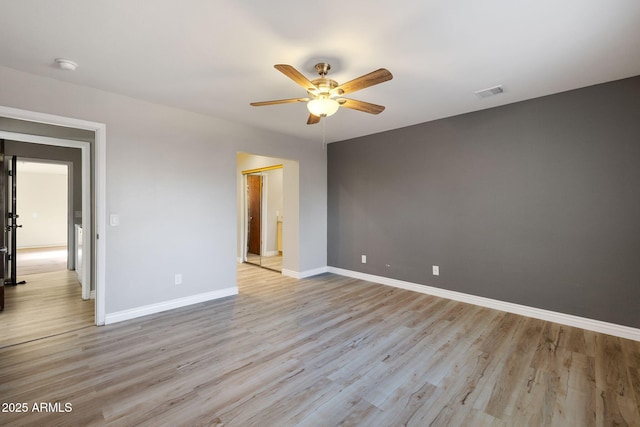 empty room featuring a ceiling fan, light wood-style flooring, visible vents, and baseboards