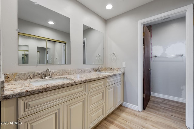 bathroom featuring double vanity, baseboards, a sink, and wood finished floors