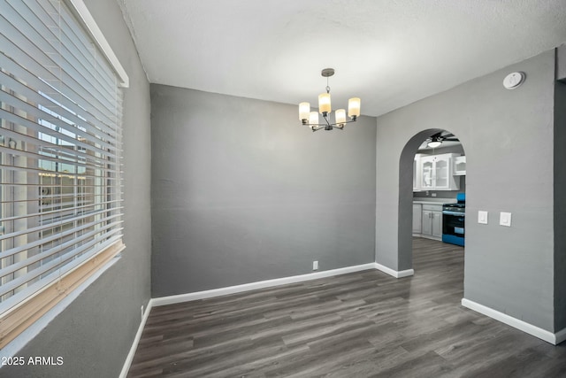 unfurnished dining area with dark wood-type flooring and an inviting chandelier