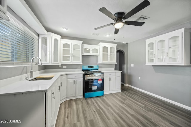 kitchen with ceiling fan, sink, stainless steel range with gas stovetop, light hardwood / wood-style flooring, and white cabinets