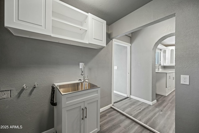 kitchen featuring white cabinets, sink, and light hardwood / wood-style flooring