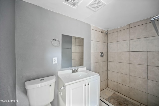 bathroom with vanity, toilet, and tiled shower