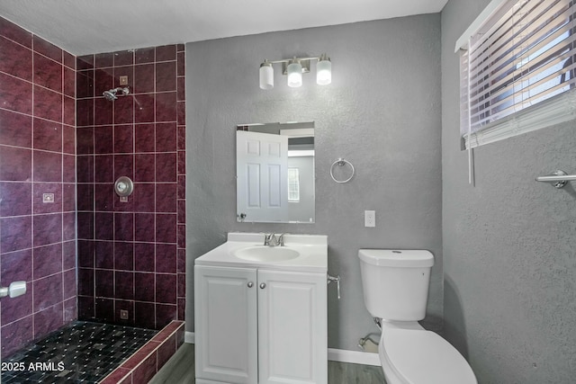 bathroom with toilet, vanity, and a tile shower