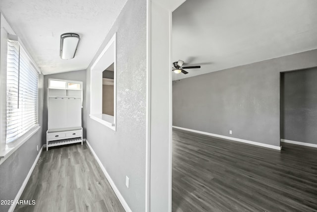 corridor featuring a textured ceiling, dark hardwood / wood-style floors, and lofted ceiling