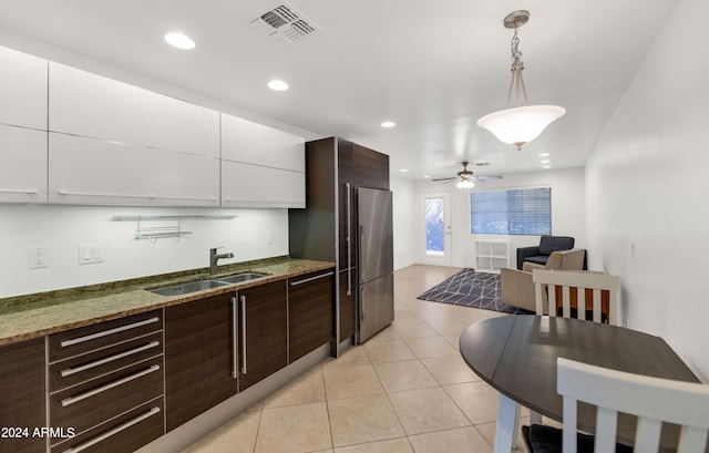 kitchen featuring ceiling fan, white cabinets, sink, decorative light fixtures, and built in fridge