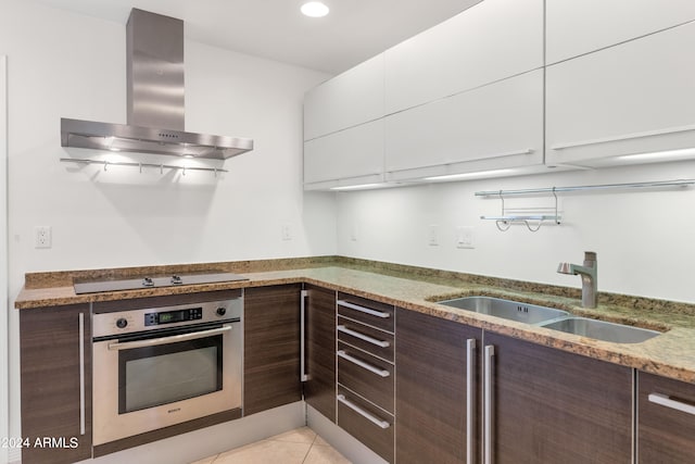 kitchen featuring oven, white cabinets, wall chimney exhaust hood, sink, and black electric stovetop