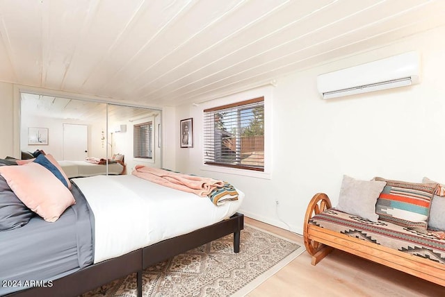 bedroom featuring a closet, wood-type flooring, and an AC wall unit