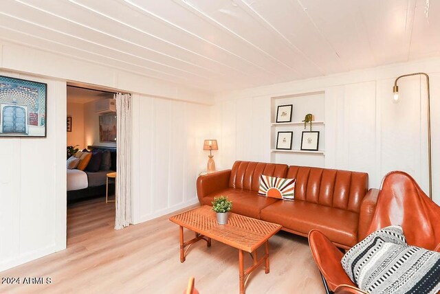 living room with a wall mounted AC and light wood-type flooring