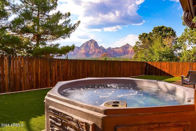 view of pool with a mountain view, a hot tub, and a yard