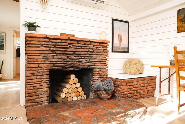 room details with hardwood / wood-style floors, wooden walls, and a fireplace