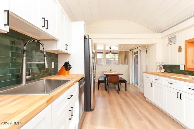 kitchen featuring vaulted ceiling, light hardwood / wood-style floors, sink, white cabinetry, and wooden counters