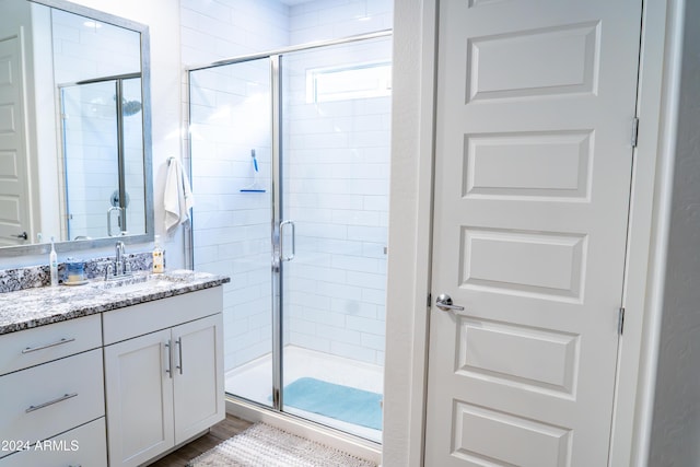 bathroom featuring vanity, hardwood / wood-style flooring, and a shower with door