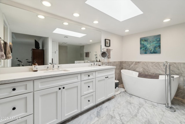 bathroom with vanity, a tub to relax in, and a skylight