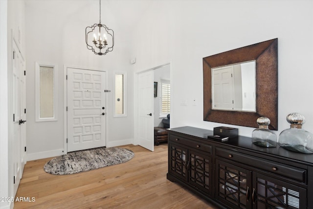 entryway featuring a high ceiling, a notable chandelier, and light wood-type flooring