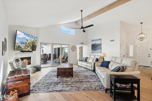 living room with high vaulted ceiling, ceiling fan with notable chandelier, light hardwood / wood-style floors, and beamed ceiling