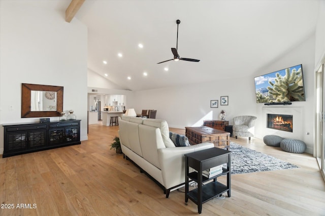 living room featuring ceiling fan, high vaulted ceiling, beamed ceiling, and light wood-type flooring