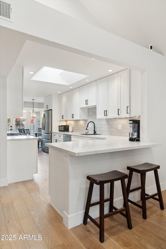 kitchen with stainless steel appliances, kitchen peninsula, a breakfast bar area, and white cabinets