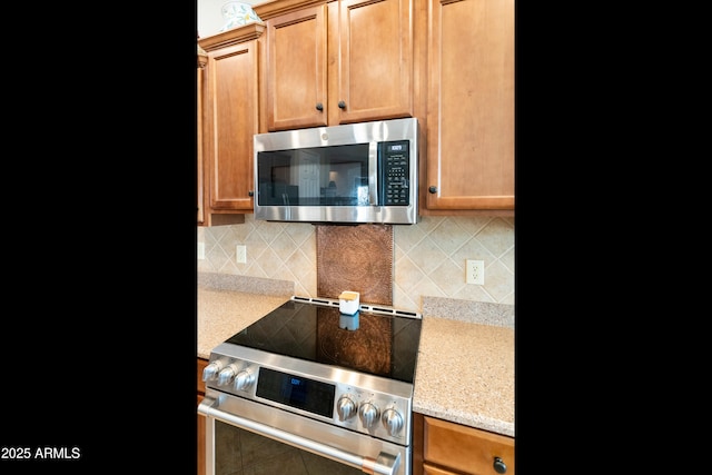 kitchen with stainless steel appliances, light stone countertops, and decorative backsplash