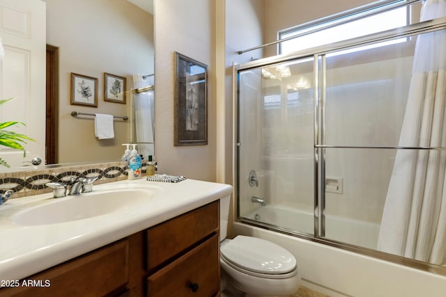 full bathroom featuring vanity, combined bath / shower with glass door, and toilet