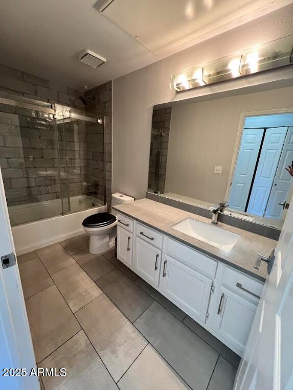 full bathroom featuring enclosed tub / shower combo, toilet, vanity, and tile patterned floors