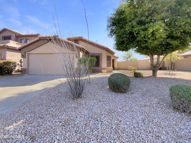 view of front of home with stucco siding, an attached garage, concrete driveway, and fence