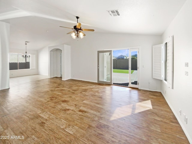 unfurnished living room featuring light wood-type flooring, visible vents, ceiling fan with notable chandelier, arched walkways, and lofted ceiling