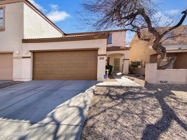 mediterranean / spanish-style home featuring concrete driveway, an attached garage, a tile roof, and stucco siding