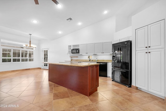 kitchen featuring decorative light fixtures, a center island, black appliances, light stone countertops, and white cabinets