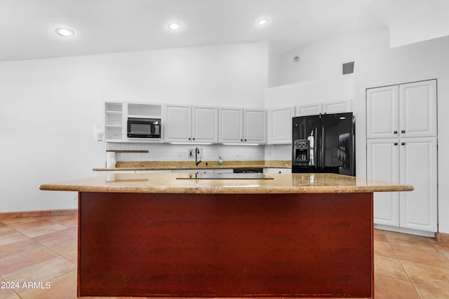 kitchen featuring white cabinetry, light stone counters, a kitchen island with sink, and black appliances