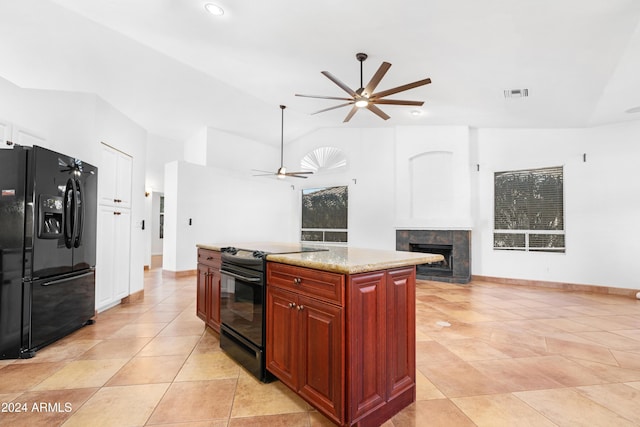 kitchen with vaulted ceiling, a fireplace, a center island, ceiling fan, and black appliances