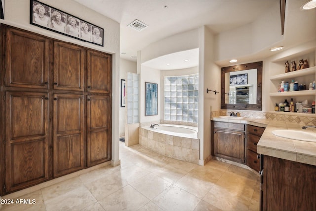 bathroom featuring tiled tub, tile patterned flooring, vanity, and built in shelves