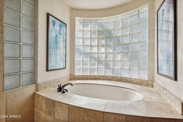 bathroom featuring a healthy amount of sunlight and tiled bath