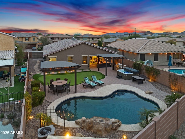 pool at dusk featuring a fenced in pool, a patio, a hot tub, an outdoor fire pit, and a fenced backyard