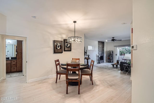 8653 E Royal Palm Rd Unit 1030, Scottsdale, AZ 85258 - dining room with ceiling fan, light wood-style flooring, a chandelier, and a large fireplace