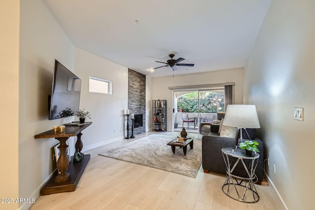 8653 E Royal Palm Rd Unit 1030, Scottsdale, AZ 85258 - living room with ceiling fan, a stone fireplace, and light wood-type flooring