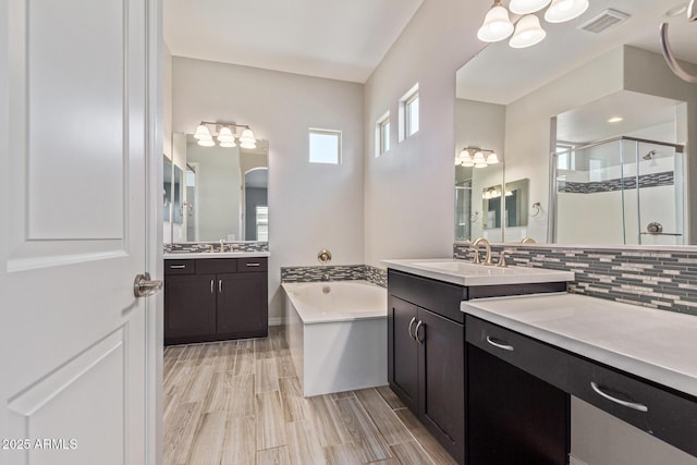 bathroom featuring visible vents, backsplash, a sink, a shower stall, and a bath