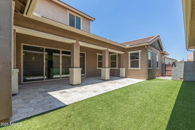 back of house with fence, a patio, a lawn, and stucco siding