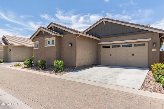 view of front of home with a garage, concrete driveway, a tiled roof, and stucco siding