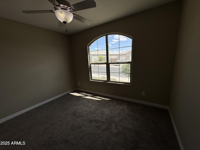carpeted spare room featuring baseboards and a ceiling fan