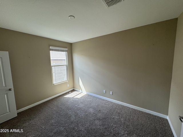 spare room with baseboards, visible vents, and dark carpet