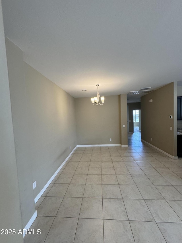 empty room featuring light tile patterned floors, baseboards, and an inviting chandelier