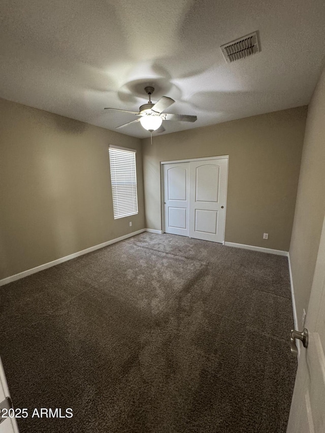 unfurnished bedroom with visible vents, a closet, baseboards, ceiling fan, and carpet