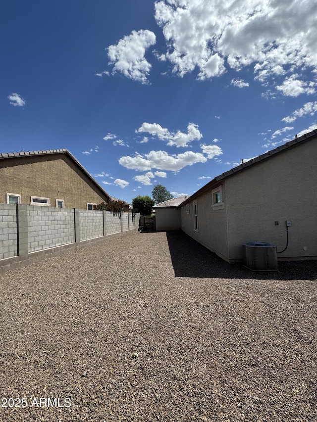 view of yard with central AC and fence