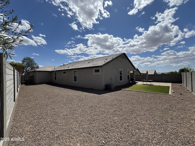 back of property with a fenced backyard, a patio, and central AC
