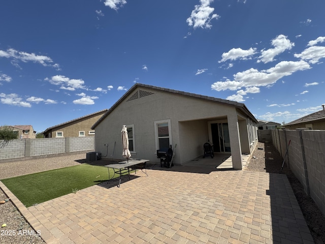 rear view of property with central air condition unit, a fenced backyard, a patio area, and stucco siding