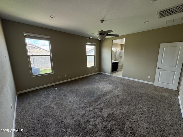 unfurnished bedroom featuring baseboards, carpet, ensuite bath, and visible vents